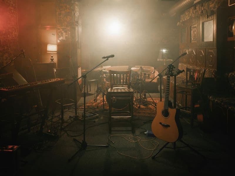 An acoustic guitar on a stand in a warmly lit music studio
